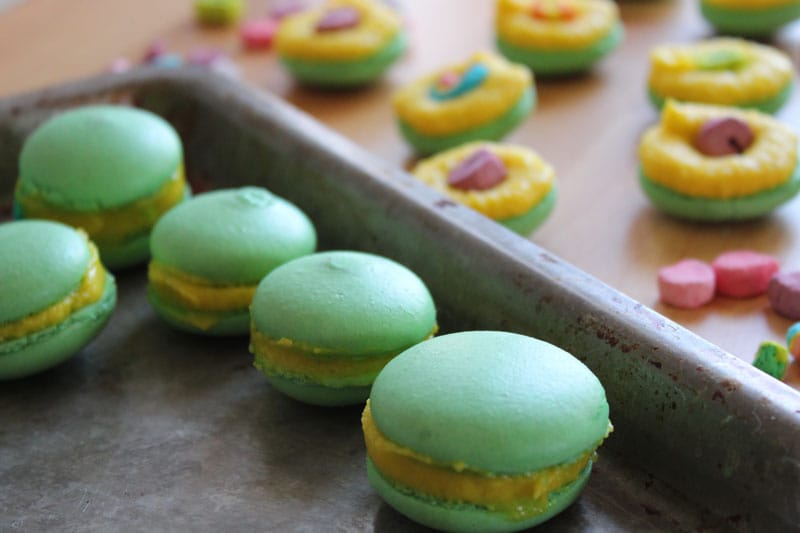 A tray of lucky charm macaroons and marshmallows sprinkled around